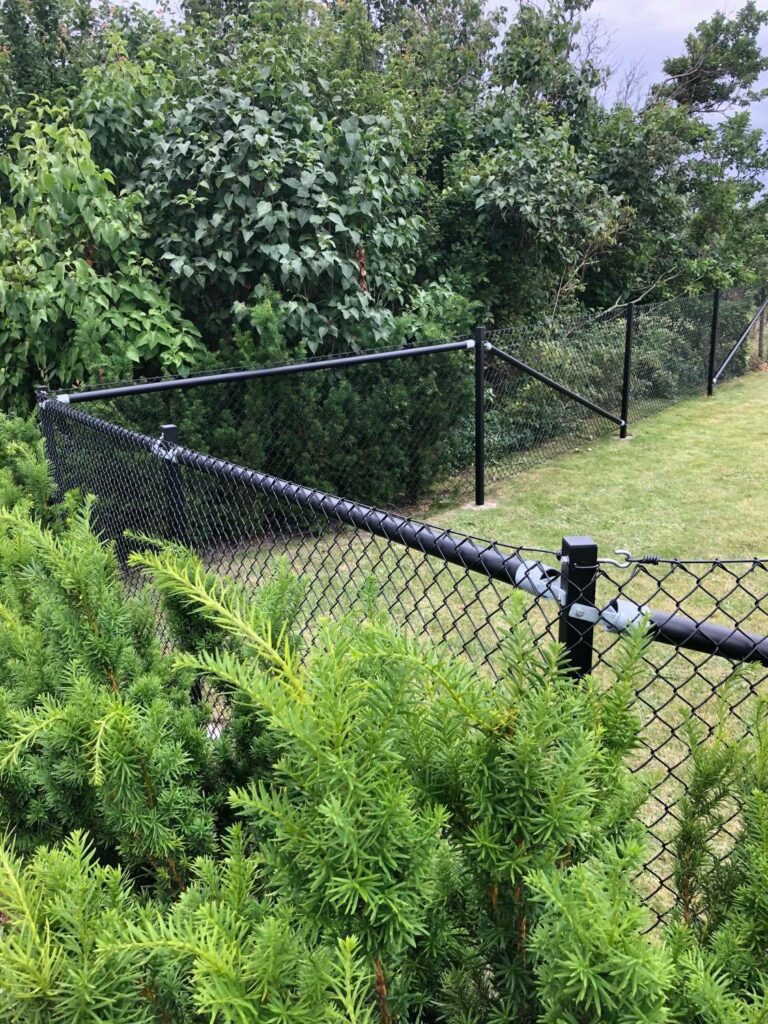 Ett svart sängsel som skiljer en privatpersons tomt åt från omgivande natur.