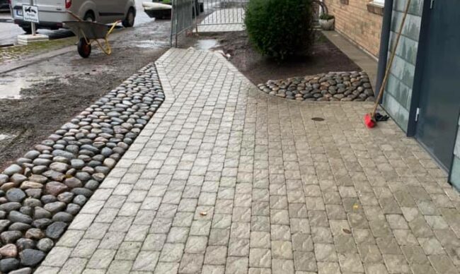 Färdig stenläggning som visar en stenlagd entré utanför en byggnad